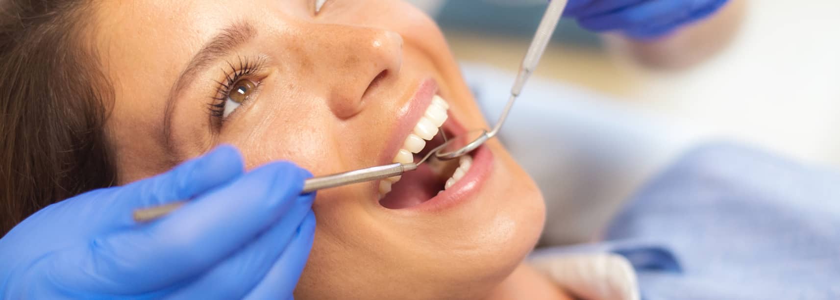 woman at the dentist getting teeth checked and fluoride treatment
